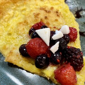 gluten and dairy free dutch baby pancake with berries and coconut on a plate